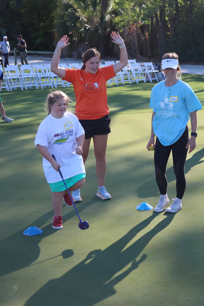 A child celebrates with volunteers after making a putt.